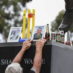 
              A man places a set of cricket stumps and a photos at the statue of Shane Warne outside the Melbourne Cricket Ground in Melbourne, Australia, Saturday, March 5, 2022. Warne, widely regarded as one of the greatest players, most astute tacticians and ultimate competitors in the long history of cricket, has died of a suspected heart attack Friday, March 4, 2022, in Koh Samui, Thailand. He was 52. (AP Photo/Asanka Brendon Ratnayake)
            