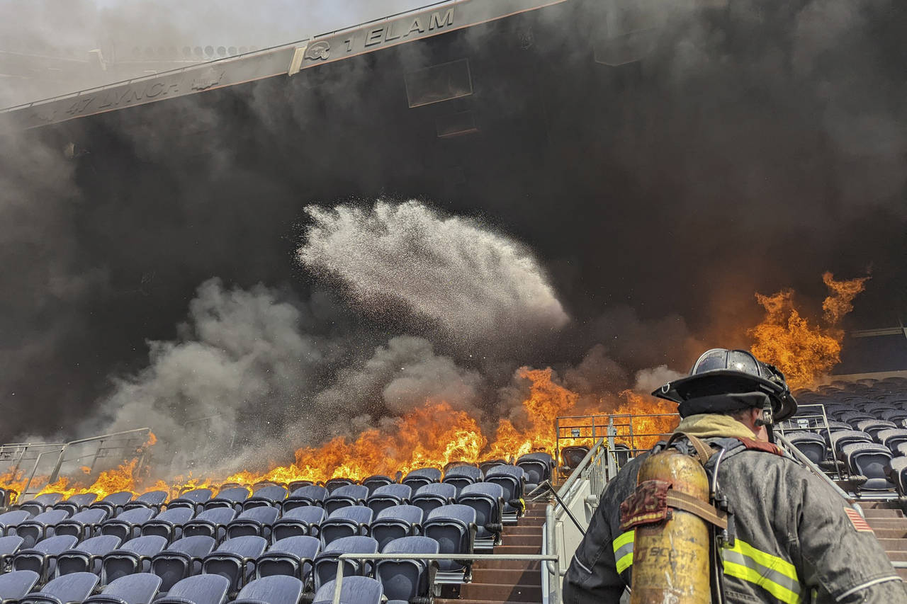 In this photo provided by the Denver Fire Department, firefighters battle flames at Empower Field a...