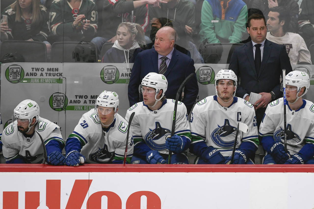 Vancouver Canucks coach Bruce Boudreau, top left, watches the team's NHL hockey game against the Mi...