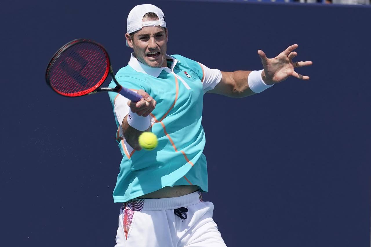 John Isner, of the United States, returns the ball to Hugo Gaston, of France, during the Miami Open...