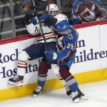 
              Colorado Avalanche center Nathan MacKinnon, left, pins Edmonton Oilers right wing Kailer Yamamoto to the boards in the third period of an NHL hockey game Monday, March 21, 2022, in Denver. (AP Photo/David Zalubowski)
            