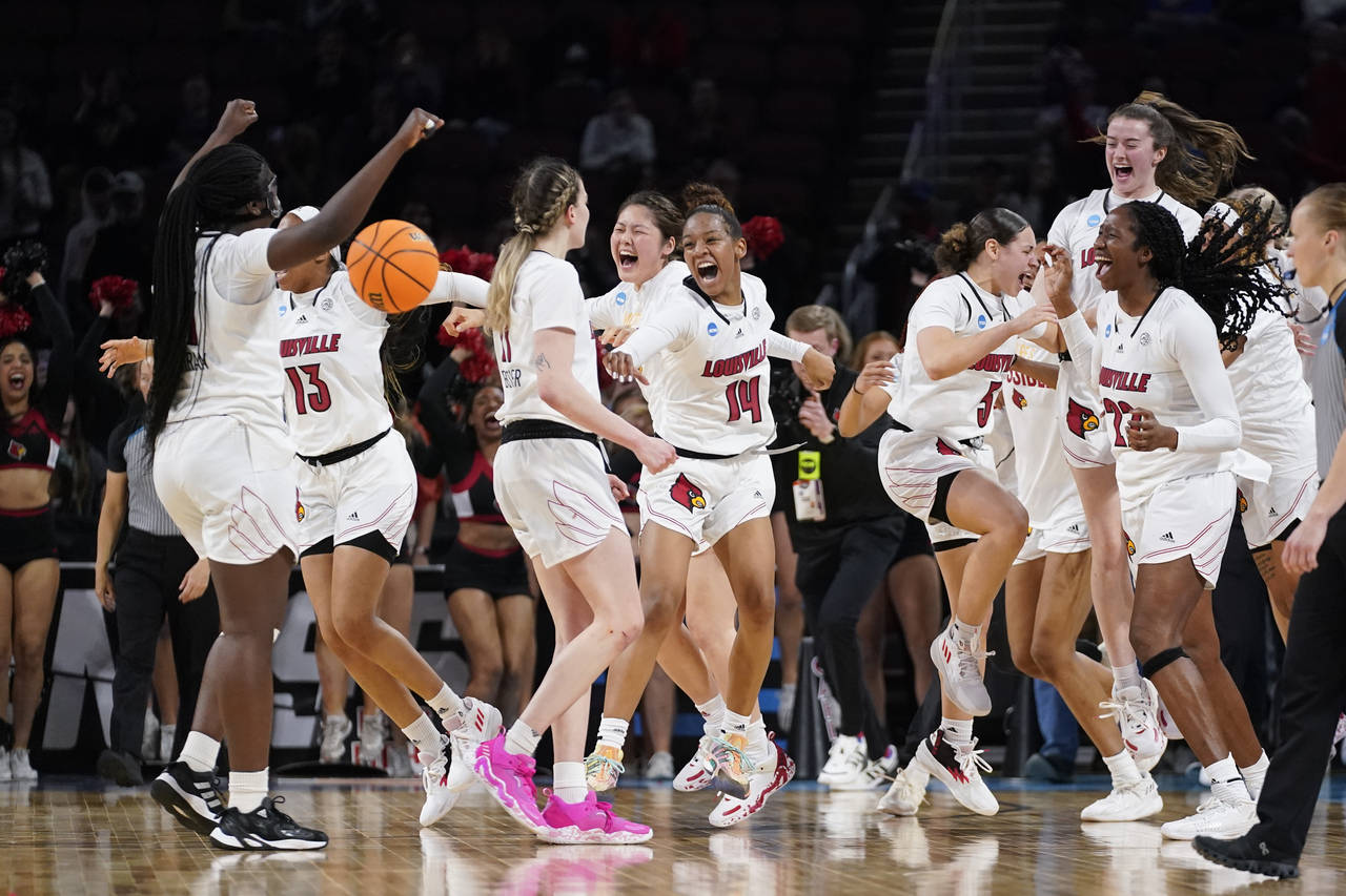 Louisville players celebrate their 62-50 win against Michigan after a college basketball game in th...