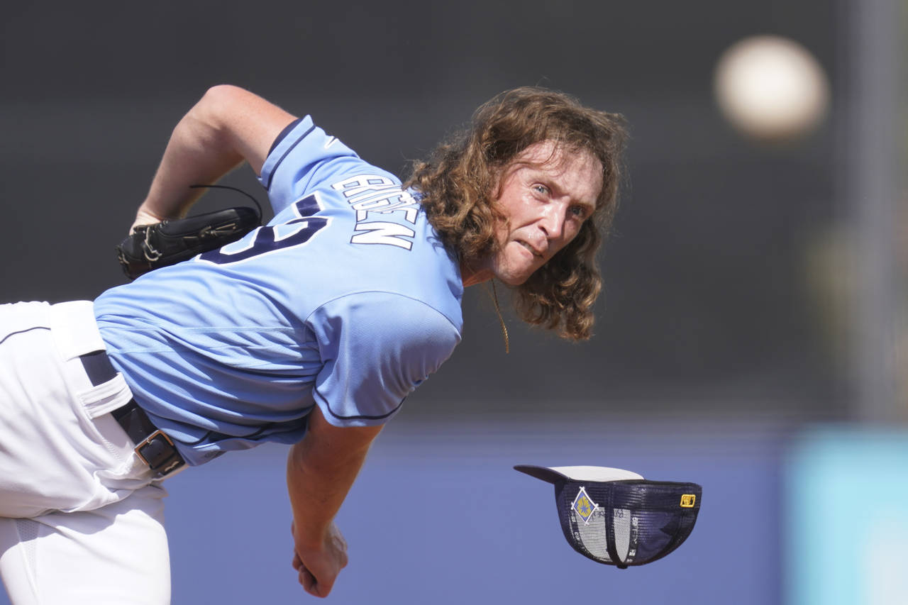 Tampa Bay Rays pitcher Trevor Brigden loses his hat as he delivers a pitch in the ninth inning of a...