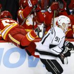 
              Los Angeles Kings' Carl Grundstrom, right, checks Calgary Flames' Sean Monahan into the bench during the first period of an NHL hockey game Thursday, March 31, 2022, in Calgary, Alberta. (Jeff McIntosh/The Canadian Press via AP)
            