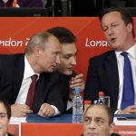 
              FILE - Russian President Vladmir Putin, left, and British Prime Minister David Cameron watch the judo during the men's 100-kg judo competition at the 2012 Summer Olympics, Aug. 2, 2012, in London. The International Judo Federation has removed the titles and jobs Vladimir Putin and long-time Kremlin-supporting oligarch Arkady Rotenberg held at the organization, the governing body said in a statement late Sunday March 6, 2022. (AP Photo/Ng Han Guan, File)
            