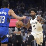 
              Brooklyn Nets guard Kyrie Irving (11) drives in front of Orlando Magic guard R.J. Hampton (13) during the first half of an NBA basketball game Tuesday, March 15, 2022, in Orlando, Fla. (AP Photo/Phelan M. Ebenhack)
            