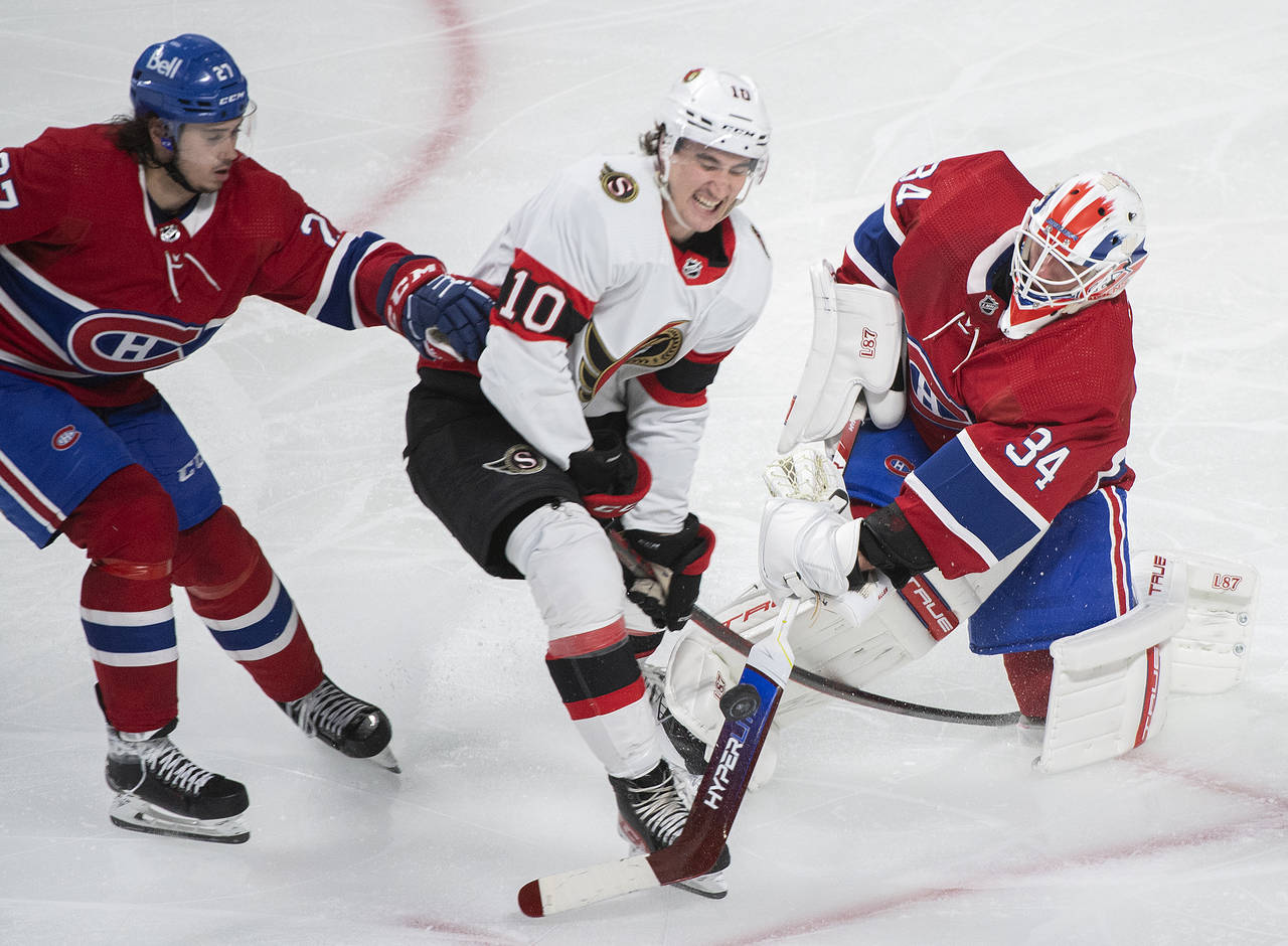 Montreal Canadiens goaltender Jake Allen clears the puck as Ottawa Senators' Alex Formenton (10) an...