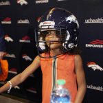
              Sienna Wilson, daughter of Denver Broncos new starting quarterback Russell Wilson, tries on a helmet after a news conference Wednesday, March 16, 2022, at the team's headquarters in Englewood, Colo. (AP Photo/David Zalubowski)
            