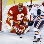 
              Edmonton Oilers' Kailer Yamamoto, right, tries to get the puck past Calgary Flames goalie Jacob Markstrom during the second period of an NHL hockey game Saturday, March 26, 2022, in Calgary, Alberta. (Jeff McIntosh/The Canadian Press via AP)
            