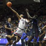 
              Connecticut's Tyler Polley (12) is defended by DePaul's Yor Anei (10) during the first half of an NCAA college basketball game Saturday, March 5, 2022, in Storrs, Conn. (AP Photo/Stew Milne)
            