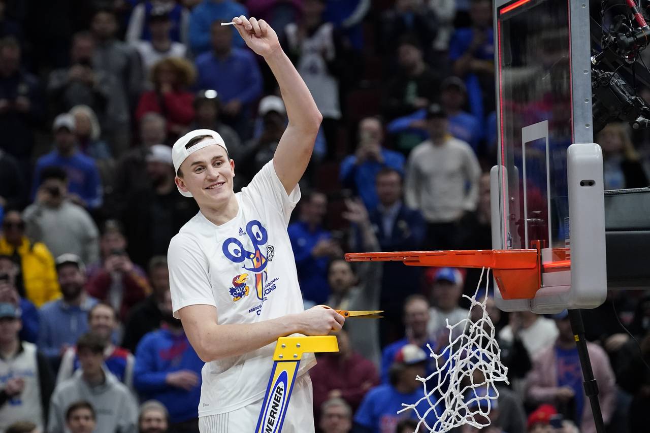 Kansas' Mitch Lightfoot cuts down the net after a college basketball game in the Elite 8 round of t...