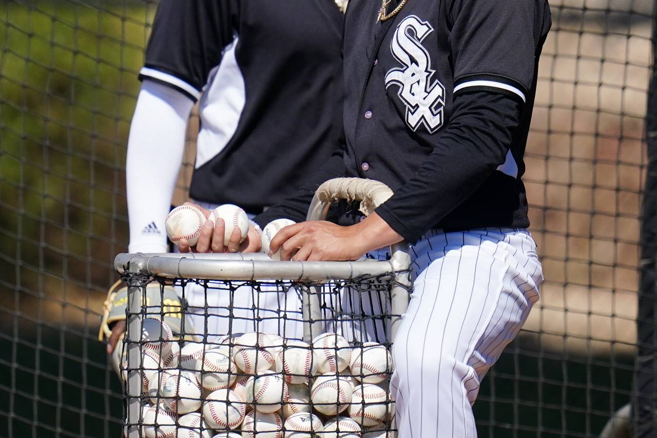 Chicago White Sox minor league players put baseballs back in the basket during batting practice at ...