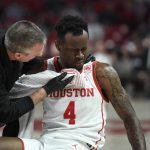 
              Houston guard Taze Moore (4) is attended to on the court after being struck on the mouth while going up for rebound against Cincinnati during the first half of an NCAA college basketball game Tuesday, March 1, 2022, in Houston. (AP Photo/Justin Rex)
            