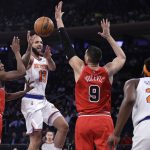 
              New York Knicks guard Evan Fournier (13) passes the ball between Chicago Bulls guard Ayo Dosunmu (12) and center Nikola Vucevic (9) during the first half of an NBA basketball game Monday, March 28, 2022, in New York. (AP Photo/Adam Hunger)
            