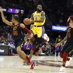 
              Los Angeles Lakers' LeBron James (6) passes the ball against Cleveland Cavaliers' Isaac Okoro (35) and Lamar Stevens (8) during the second half of an NBA basketball game, Monday, March 21, 2022, in Cleveland. (AP Photo/Ron Schwane)
            