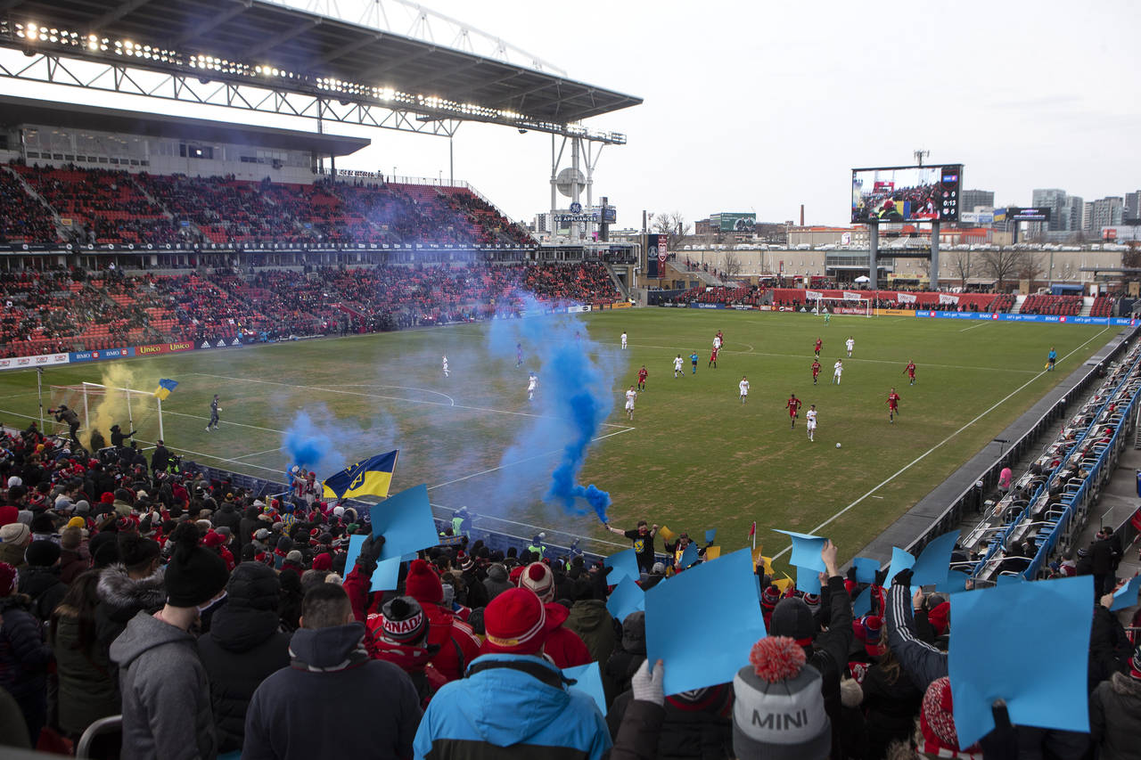 Toronto FC's fans set off blue-and-yellow flares and hold up colored cards to show their support fo...