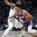 
              Phoenix Suns guard Devin Booker, front, drives past Denver Nuggets forward Aaron Gordon during the second half of an NBA basketball game Thursday, March 24, 2022, in Denver. (AP Photo/David Zalubowski)
            