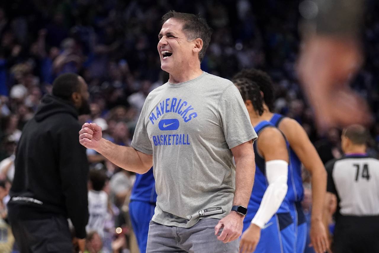 Dallas Mavericks team owner Mark Cuban celebrates on the court during a time out after the Maverick...