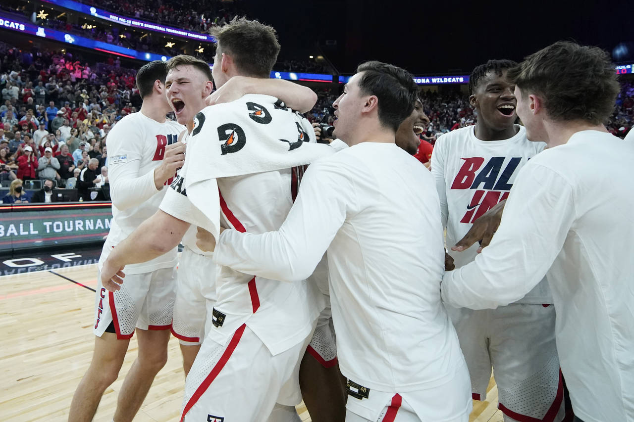 Arizona players celebrate after defeating UCLA in an NCAA college basketball game in the championsh...