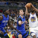 
              Golden State Warriors forward Andrew Wiggins, right, looks for a shot against Orlando Magic forward Franz Wagner, center, and center Mo Bamba (5) during the first half of an NBA basketball game, Tuesday, March 22, 2022, in Orlando, Fla. (AP Photo/John Raoux)
            