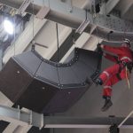 
              A man rappels down to a group of speakers that hang from the ceiling of the arena after play was suspended between the Toronto Raptors and the Indiana Pacers and the building was evacuated of fans, during the first half of an NBA basketball game Saturday, March 26, 2022, in Toronto. (Frank Gunn/The Canadian Press via AP)
            