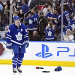 
              Toronto Maple Leafs forward Auston Matthews (34) celebrates his hat trick as fans throw their hats on the ice while during the third period of an NHL hockey game against the Seattle Kraken, Tuesday, March 8, 2022, in Toronto. (Nathan Denette/The Canadian Press via AP)
            