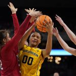 
              Michigan's Naz Hillmon (00) fights her way to the basket as South Dakota's Kyah Watson, left, and Grace Larkins defend during the second half of a college basketball game in the Sweet 16 round of the NCAA women's tournament Saturday, March 26, 2022, in Wichita, Kan. (AP Photo/Jeff Roberson)
            
