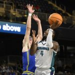 
              UNC Wilmington guard Mike Okauru (4) goes to the basket against Delaware forward Andrew Carr, left, during the first half of an NCAA college basketball game in the championship of the Colonial Athletic Association conference tournament, Tuesday, March 8, 2022, in Washington. (AP Photo/Nick Wass)
            