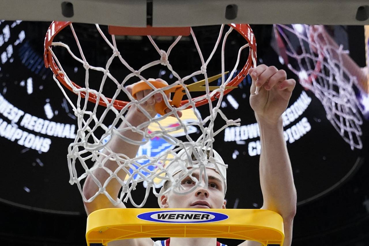 Kansas' Christian Braun cuts down the net after a college basketball game in the Elite 8 round of t...