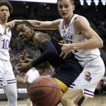 
              Kansas forward Mitch Lightfoot, right, and West Virginia forward Gabe Osabuohien, left, chase after a loose ball during the first half of an NCAA college basketball game in the quarterfinal round of the Big 12 Conference tournament in Kansas City, Mo., Thursday, March 10, 2022. (AP Photo/Charlie Riedel)
            