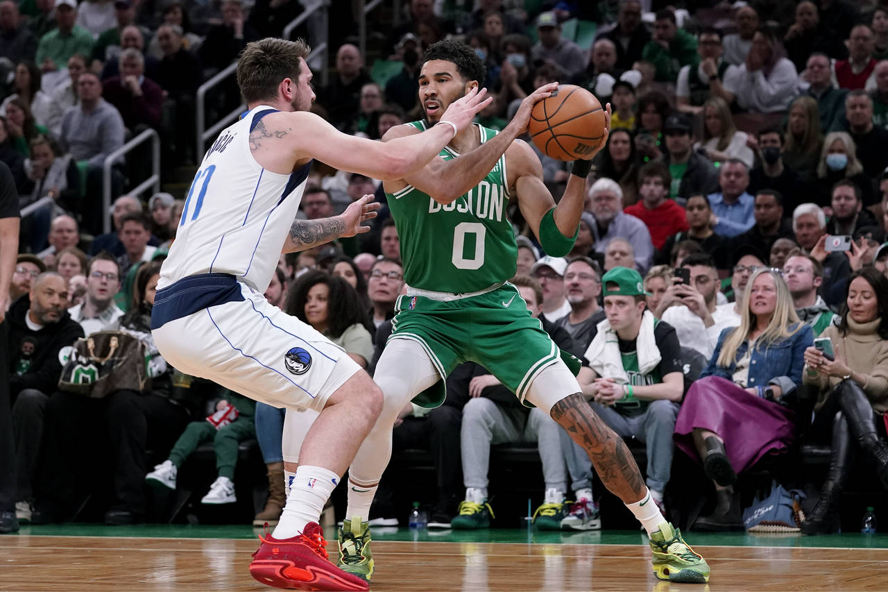 Boston Celtics forward Jayson Tatum (0) looks for an opening past Dallas Mavericks guard Luka Donci...