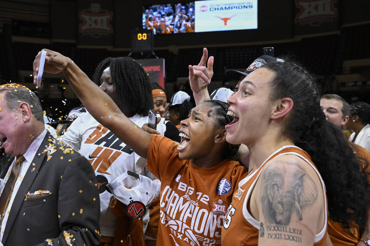 Texas guard Aliyah Matharu, holding phone, and teammate Audrey Warren, right, take selfies while ce...