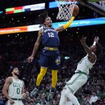 
              Memphis Grizzlies guard Ja Morant (12) threads between Boston Celtics guard Marcus Smart, right, and forward Jason Tatum (0) on a dunk during the first half of an NBA basketball game, Thursday, March 3, 2022 in Boston. (AP Photo/Charles Krupa)
            