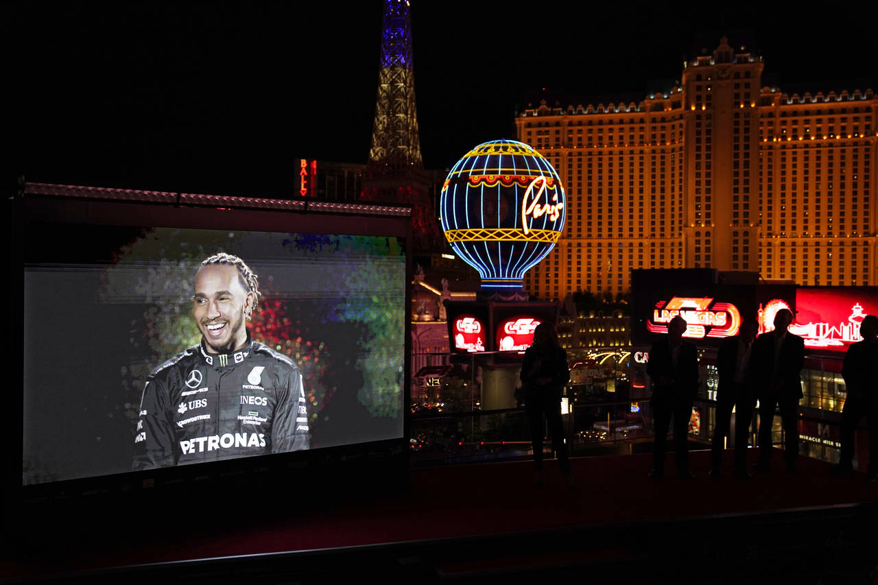 People watch as a recording of Mercedes driver Lewis Hamilton, of Britain, is projected onto a scre...