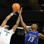 
              Delaware forward Jyare Davis (13) and UNC Wilmington guard James Baker (3) battle for the ball during the first half of an NCAA college basketball game in the championship of the Colonial Athletic Association conference tournament, Tuesday, March 8, 2022, in Washington. (AP Photo/Nick Wass)
            