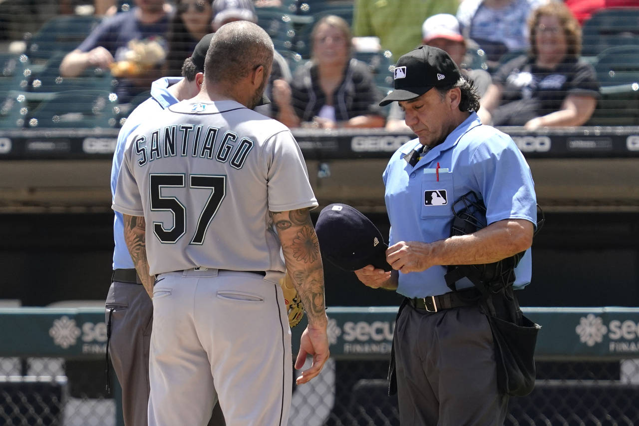 FILE - Home Plate umpire Phil Cuzzi, right, checks Seattle Mariners relief pitcher Hector Santiago'...