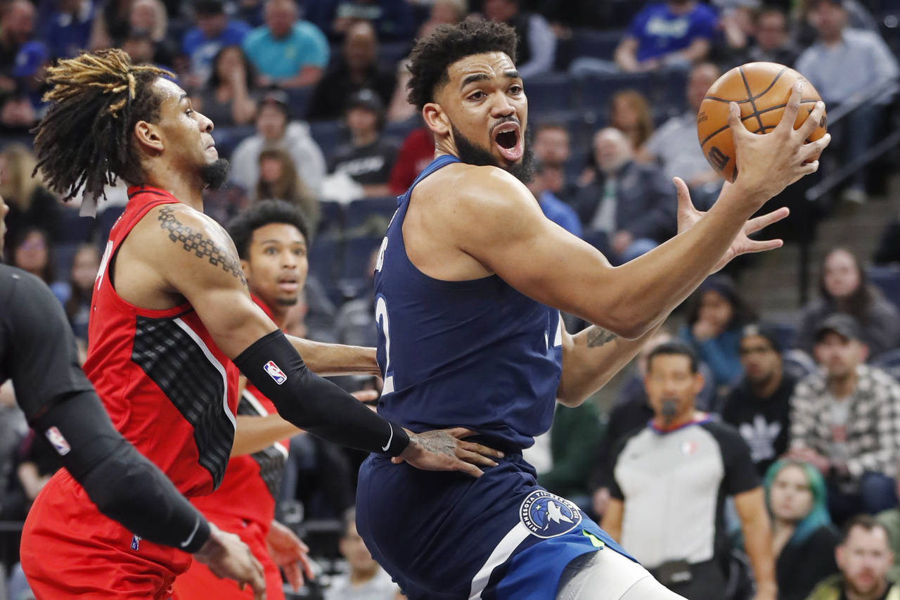 Minnesota Timberwolves center Karl-Anthony Towns, right, goes to the basket around Portland Trail B...