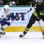 
              Dallas Stars left wing Jason Robertson (21) takes control of the puck next to Vancouver Canucks defenseman Quinn Hughes (43) during the first period of an NHL hockey game in Dallas, Saturday, March 26, 2022. (AP Photo/LM Otero)
            