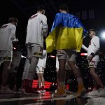 
              Maryland forward Pavlo Dziuba, front right, who was born in Kyiv, Ukraine, is draped in a flag of Ukraine prior to an NCAA college basketball game against Ohio State, Sunday, Feb. 27, 2022, in College Park, Md. (AP Photo/Julio Cortez)
            