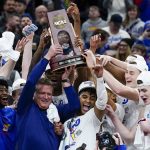 
              Kansas head coach Bill Self and players hold up the winning trophy after a college basketball game in the Elite 8 round of the NCAA tournament against Miami Sunday, March 27, 2022, in Chicago. Kansas won 76-50 to advance to the Final Four. (AP Photo/Charles Rex Arbogast)
            