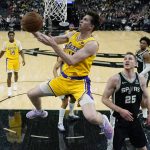 
              Los Angeles Lakers guard Austin Reaves, foreground, drives to the basket past San Antonio Spurs center Jakob Poeltl (25) during the first half of an NBA basketball game, Monday, March 7, 2022, in San Antonio. (AP Photo/Eric Gay)
            