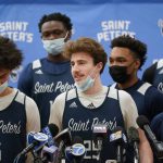 
              Surrounded by teammates, St. Peter's Doug Edert, center, speaks to reporters before NCAA college basketball  practice in Jersey City, N.J., Tuesday, March 22, 2022. (AP Photo/Seth Wenig)
            