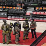 
              Firefighters and fire department officials stand on the court after play was suspended between the Toronto Raptors and the Indiana Pacers and the building was evacuated fans, during the first half of an NBA basketball game Saturday, March 26, 2022, in Toronto. (Frank Gunn/The Canadian Press via AP)
            
