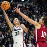 
              Connecticut guard Caroline Ducharme (33) puts up a shot against Indiana forward Aleksa Gulbe (10) during the second quarter of a college basketball game in the Sweet Sixteen round of the NCAA women's tournament, Saturday, March 26, 2022, in Bridgeport, Conn. (AP Photo/Frank Franklin II)
            