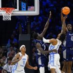 
              North Carolina's Caleb Love (2) cannot get a shot past St. Peter's KC Ndefo (11) and Fousseyni Drame (10) during the first half of a college basketball game in the Elite 8 round of the NCAA tournament, Sunday, March 27, 2022, in Philadelphia. (AP Photo/Chris Szagola)
            