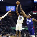 
              Golden State Warriors forward Andrew Wiggins (22) shoots from between Los Angeles Clippers center Ivica Zubac, left, and guard Terance Mann during the first half of an NBA basketball game in San Francisco, Tuesday, March 8, 2022. (AP Photo/Jed Jacobsohn)
            