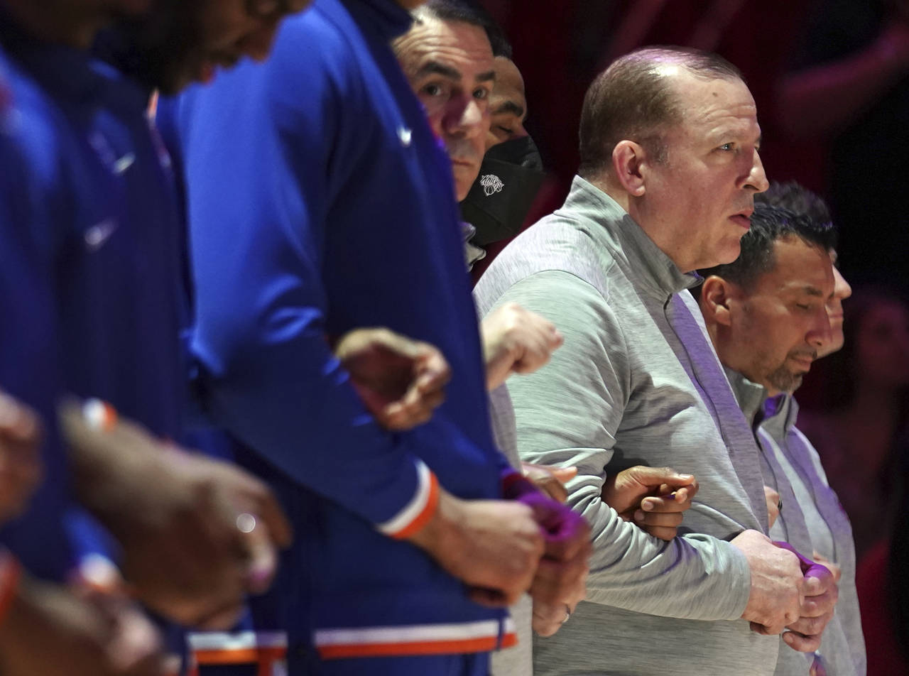 New York Knicks coach Tom Thibodeau stands arm-in-arm with players during the national anthem befor...