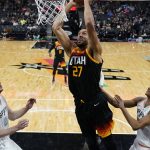 
              Utah Jazz center Rudy Gobert (27) scores over San Antonio Spurs center Jakob Poeltl, left, and guard Devin Vassell, right, during the second half of an NBA basketball game, Friday, March 11, 2022, in San Antonio. (AP Photo/Eric Gay)
            
