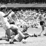 
              FILE - In this June 22, 1986 file photo, Argentina's Diego Maradona, second left, is about to score his second goal against England, during a World Cup quarterfinal soccer match against England, in Mexico City. England's Terry Butcher, left, tries to tackle Maradona, while England's goalkeeper Peter Shilton is on the ground. Gio Reyna, the son of former U.S. captain Claudio Reyna and women's national team midfielder Danielle Egan, was compared with Maradona in the '86 World Cup by U.S. coach Gregg Berhalter after a USA vs Mexico qualifying match in Mexico City on Thursday, March 24, 2022.(AP Photo/File)
            