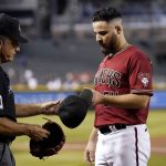
              FILE - Arizona Diamondbacks starting pitcher Humberto Castellanos, right, surrenders his hat and glove for inspection to umpire Phil Cuzzi (10) during the sixth inning of a baseball game against the Philadelphia Phillies, on Aug. 18, 2021, in Phoenix. Major League Baseball is making checks banned foreign substances on pitchers more random after watching its crackdown become less effective late last season. Last season, umpires checked all starting pitcher multiple times and all relievers either at the end of his first inning or when removed, whichever occurs first. Caps, gloves and fingertips were checked. (AP Photo/Ross D. Franklin, File)
            